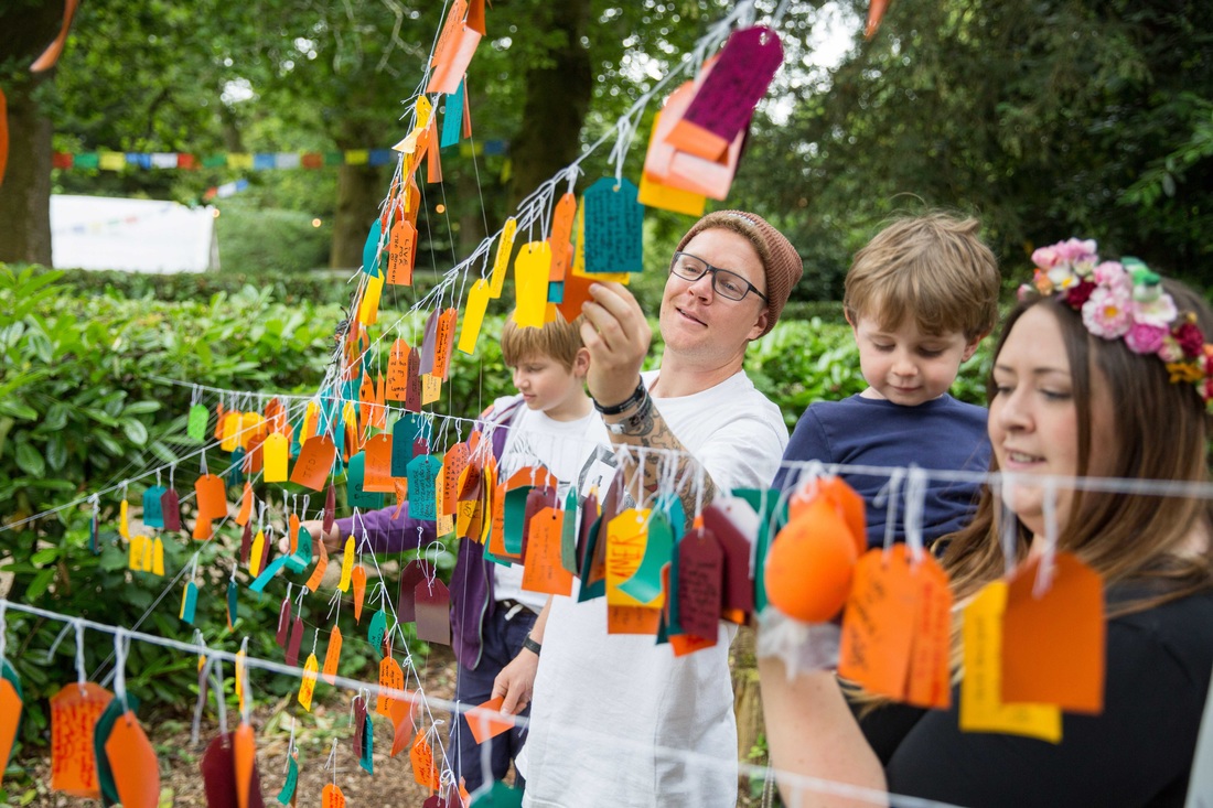 People engaging with installation made from hand written notes on luggage tags.